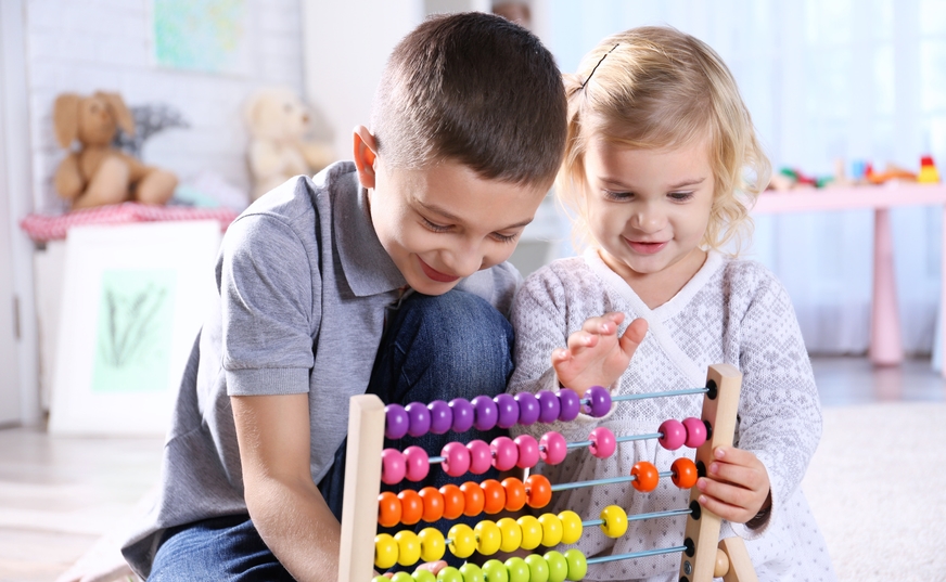 Ein Junge und ein Mädchen spielen mit einem Rechenschieber