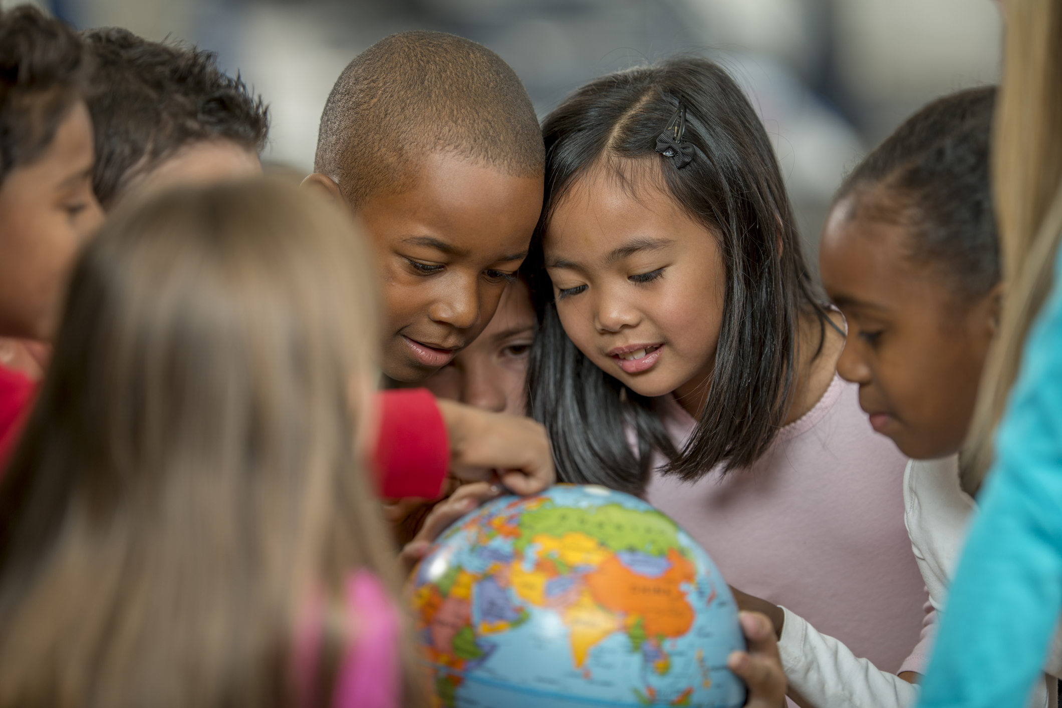 Kinder verschiedener Herkunft spielen mit einem Globus