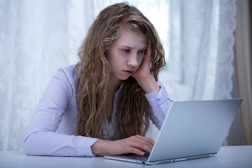 Mädchen schaut traurig auf ihren Laptop