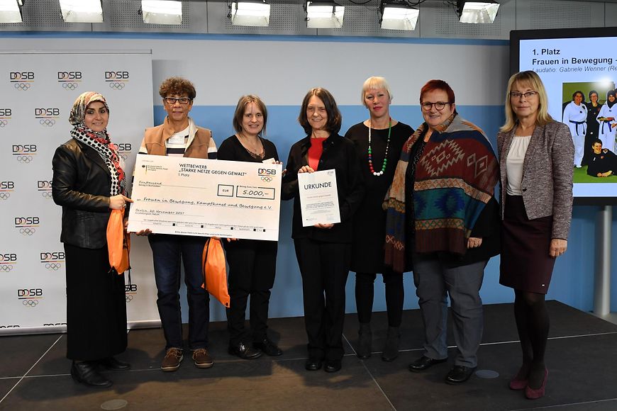 Elke Ferner mit Preisträgerinnen des Vereins "Frauen in Bewegung", einer Urkunde und einem Scheck über 5000 Euro