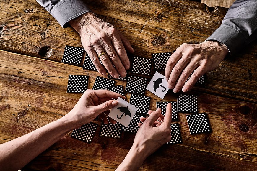 Tischsituation mit Händen von einem älteren Menschen mit Demenz und Memory-Karten.