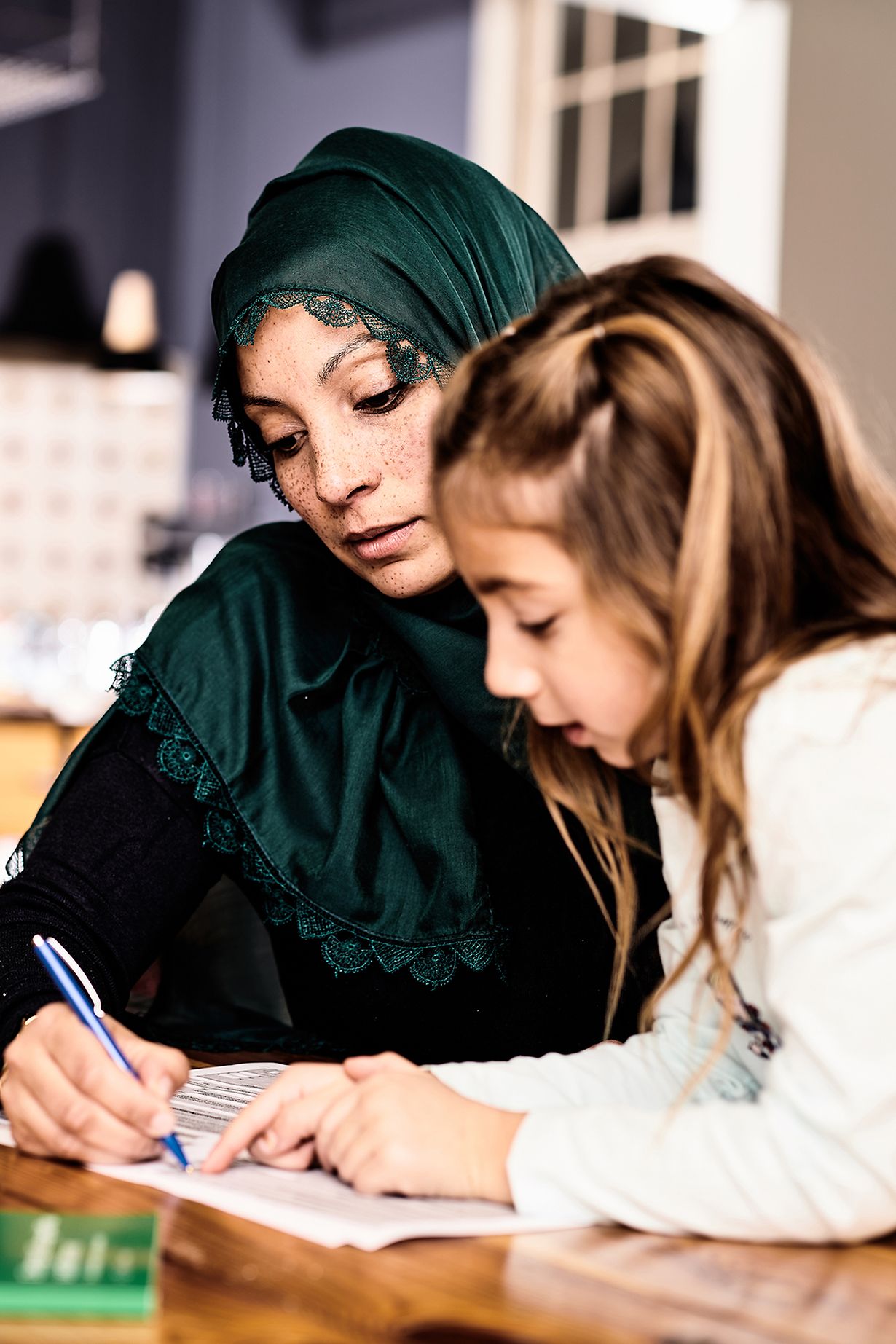 Eine Muslima füllt mit ihrer Tochter zusammen ein Dokument aus