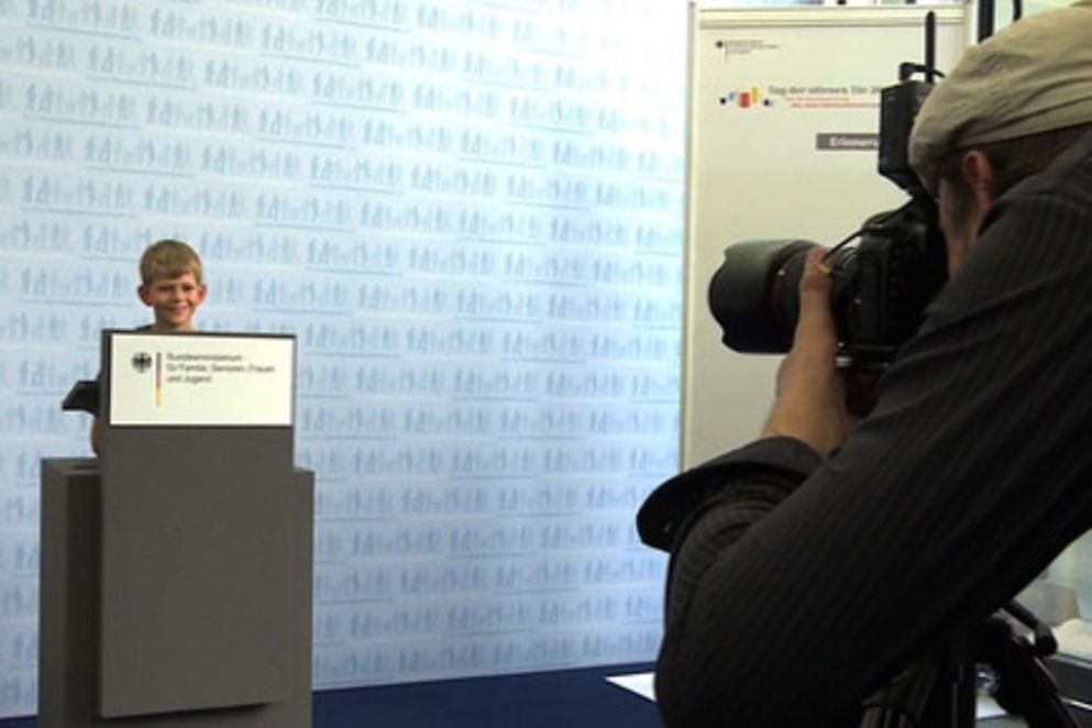 Ein Junge steht hinter einem Rednerpult im Bundesfamilienministerium und wird fotografiert