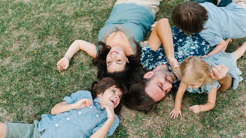 Mutter, Vater und drei Kinder spielen auf einer Wiese