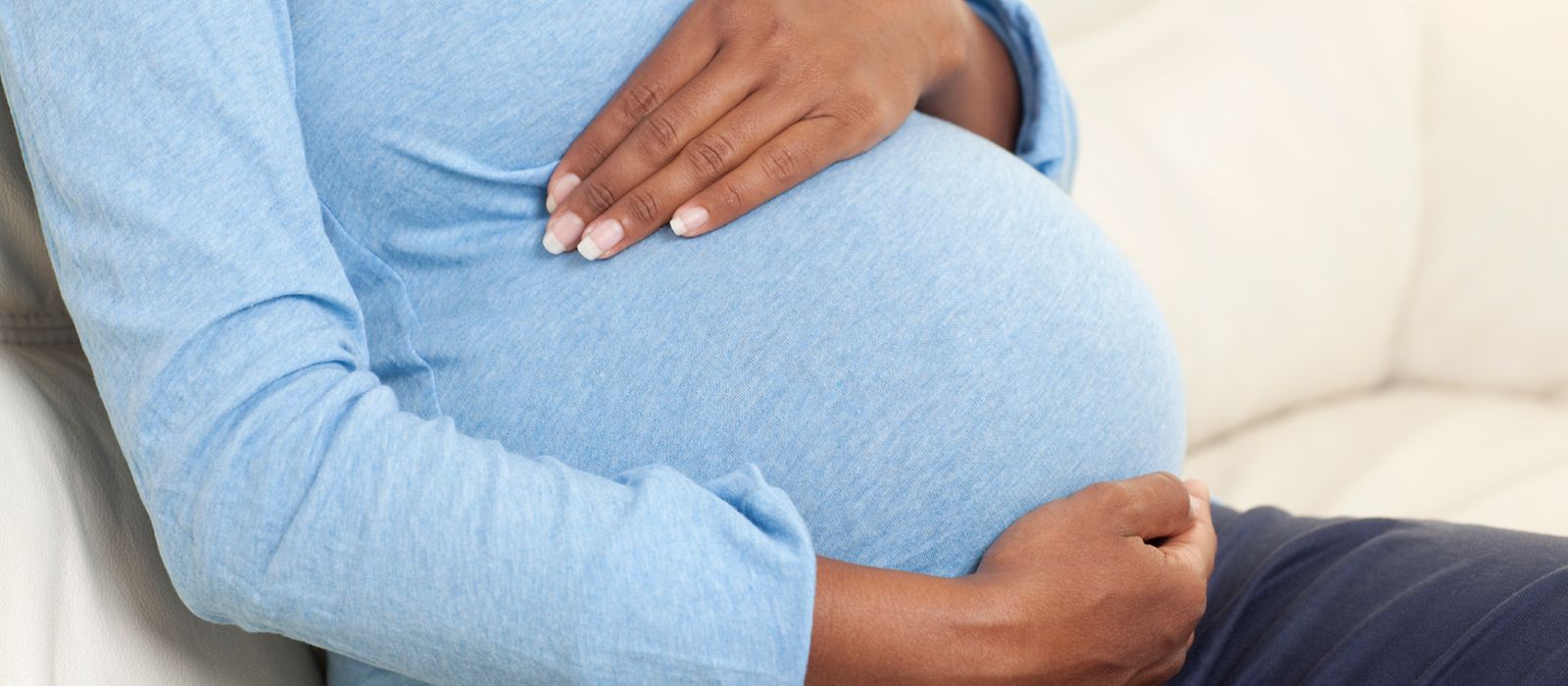 Eine schwangere Frau hält sich ihre Hände an den Bauch