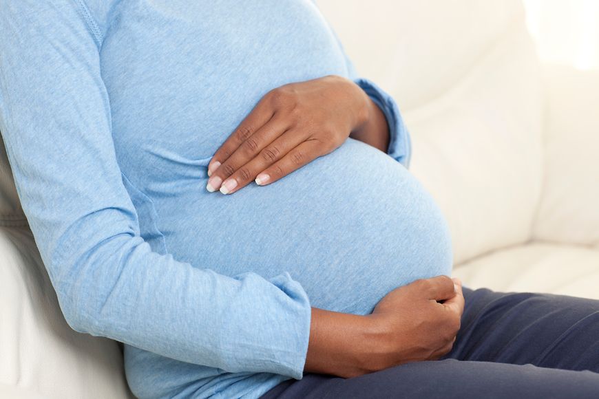Eine schwangere Frau hält sich ihre Hände an den Bauch