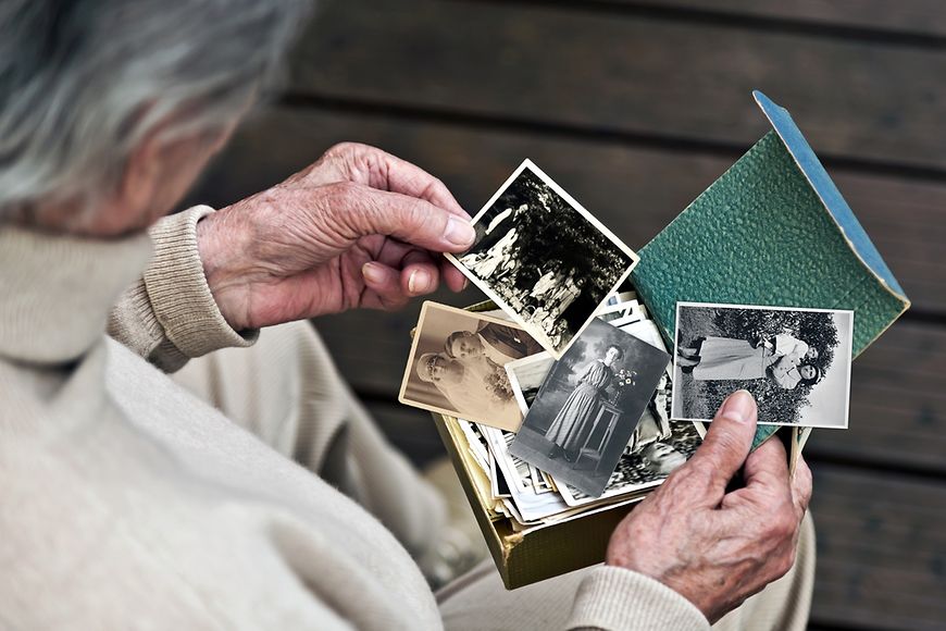 Eine alte Frau hält Schwarz-Weiß-Fotos in den Händen