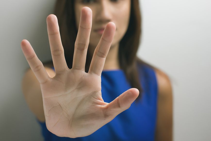 Eine Frau hält ihre Hand schützend vor die Kamera