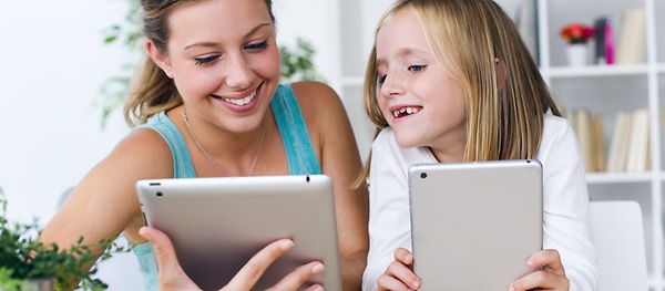 Mutter und Tochter spielen mit Tablets