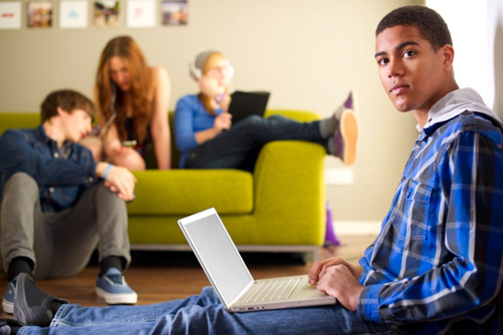 Junger Mann mit Migrationshintergrund sitzt am Laptop