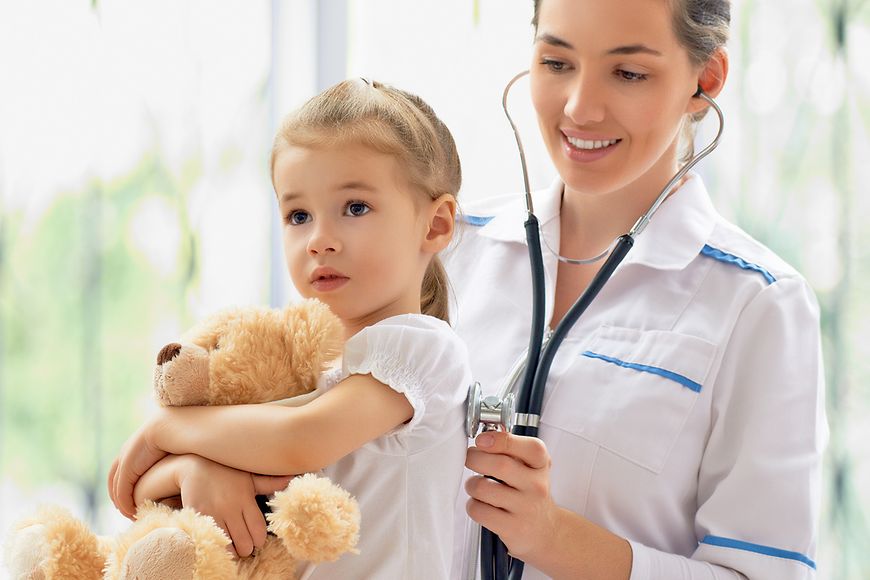 Kinderärztin untersucht Mädchen mit Teddy
