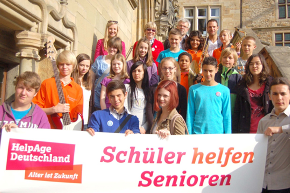 Junge Menschen zeigen ein Plakat zum Projekt "Schüler helfen Senioren"