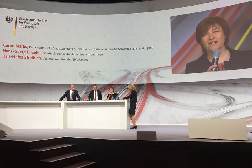 Podiumsdiskussion mit Caren Marks, Hans-Georg-Engelke und Karl-Heinz Streibich und Moderatorin mit Projektion im Hintergund