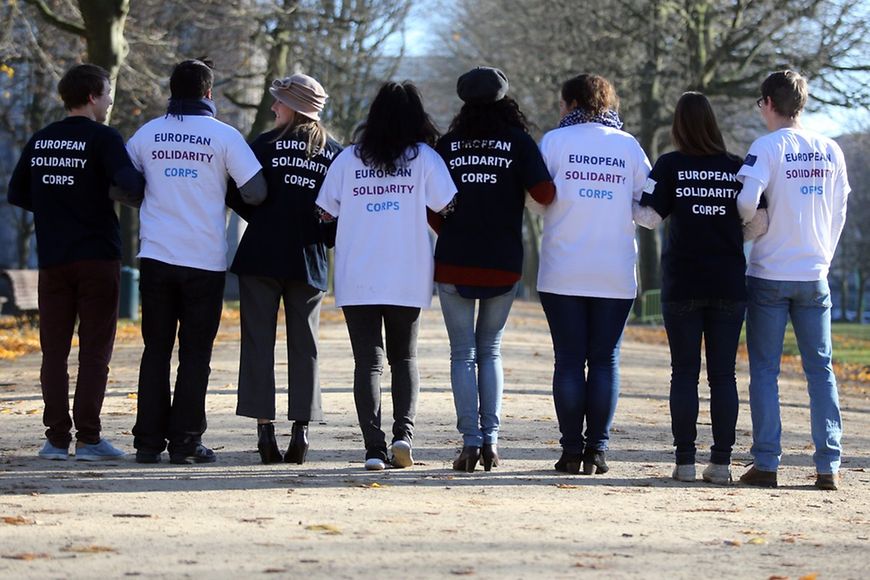 Rückenansicht von acht Jugendlichen mit abwechselnd schwarzen und weißen T-Shirts mit dem Aufdruck European Solidarity Corps