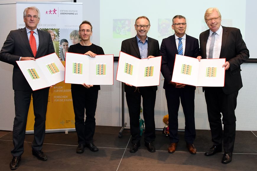 Gruppenfoto mit Dr. Ralf Kleindiek und Werner Gatzer, sie halten die Alben mit den Jugendmarken 2017 in den Händen
