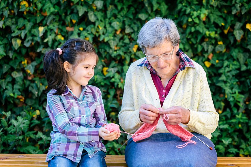 Kleines Mädchen hilft älterer Damen beim Stricken