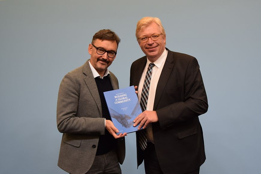 Dr. Klaus Müller und Dr. Ralf Kleindiek halten gemeinsam das Buch "Building a global community" in den Händen