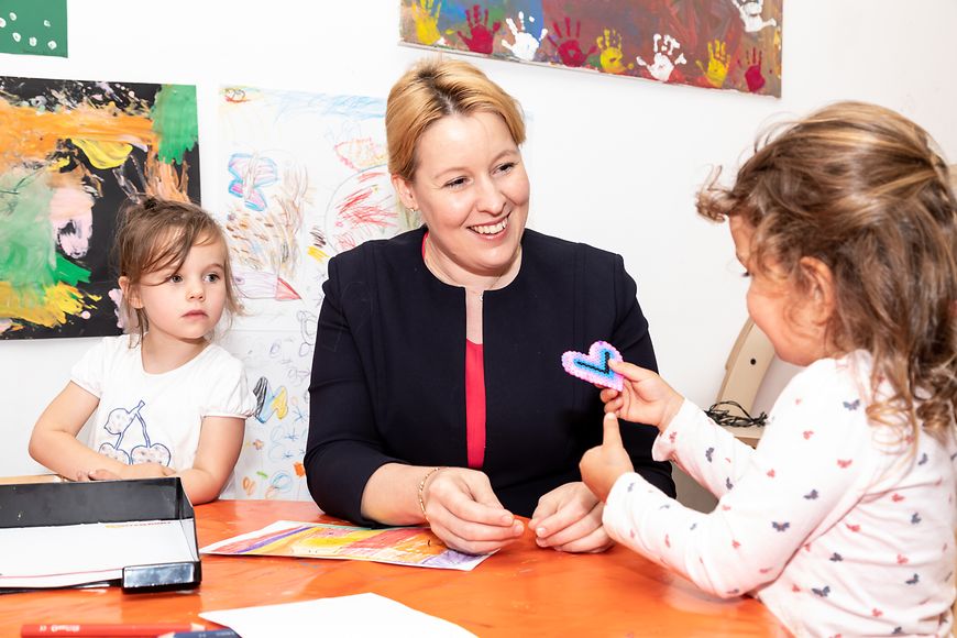 Das Bild zeigt Franziska Giffey und ein Mädchen, das ihr ein gebasteltes Herz überreicht