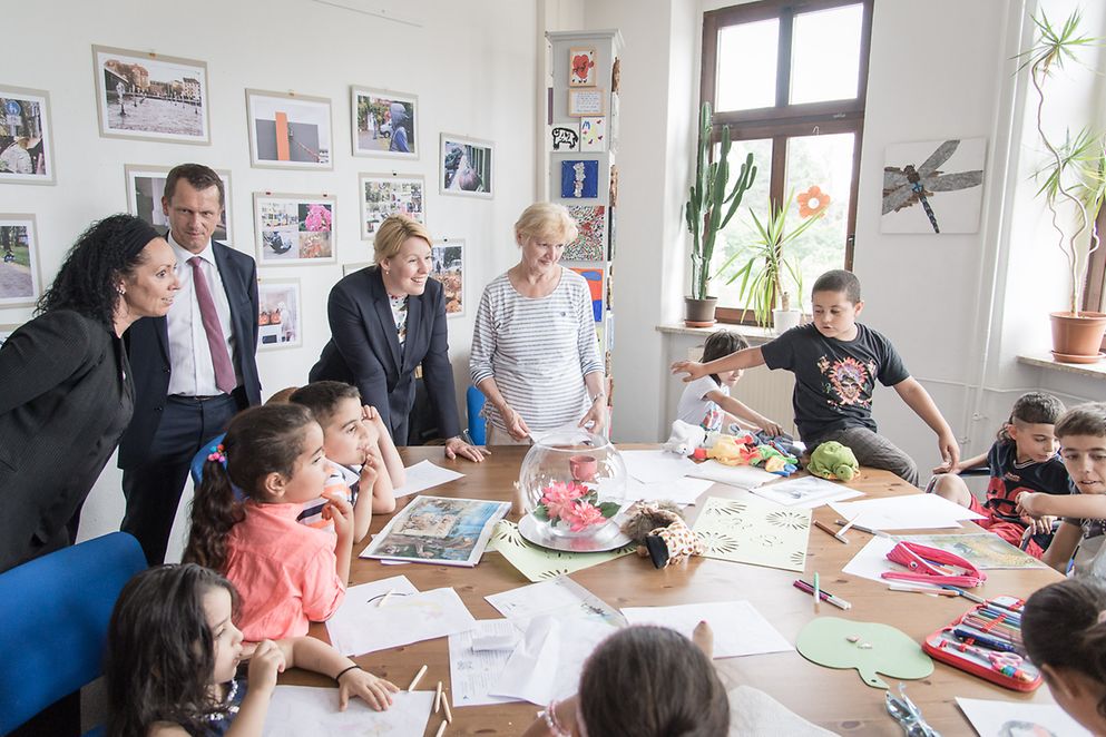 Die Ministerin mit bastelnden Kindern an einem Tisch