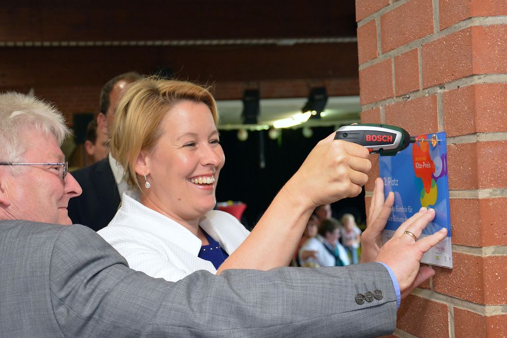 Das Bild zeigt Franziska Giffey mit einem Akku-Schrauber beim Montieren der Preisträger-Plakette