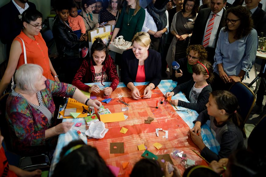 Dr. Franziska Giffey sitzt mit Kindern und älteren Menschen gemeinsam an einem Tisch beim Basteln