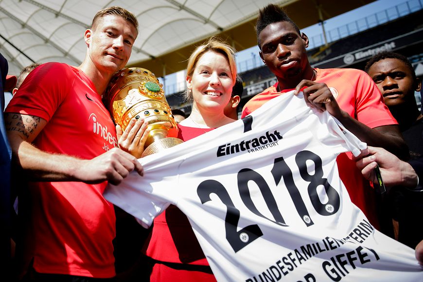 Das Bild zeigt Franziska Giffey zbd zwei Jugendliche mit einem Trikot und einem Pokal