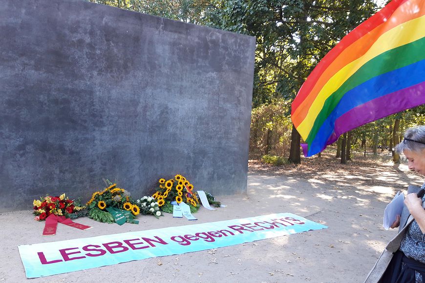 Das Bild zeigt ein Denkmal mit einem Banner davor "Lesben gegen Rechts"