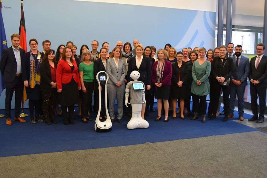 Das Bild zeigt Dr. Franziska Giffey mit mehrereren EU-Expertinnen und Experten aus dem Bereich Pflege und einem Pflegeroboter 