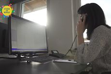 Eine Frau sitzt an einem PC und telefoniert