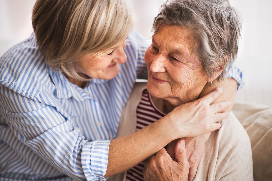 Das Bild zeigt eine jüngere Frau, die eine ältere Frau umarmt