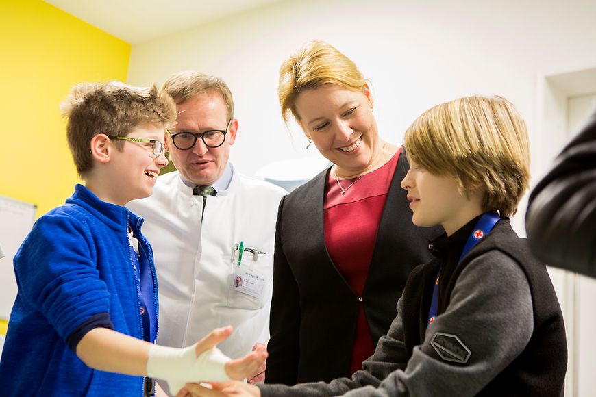 Das Bild zeigt einen Schüler, der einem anderen Schüler die Hand verbindet