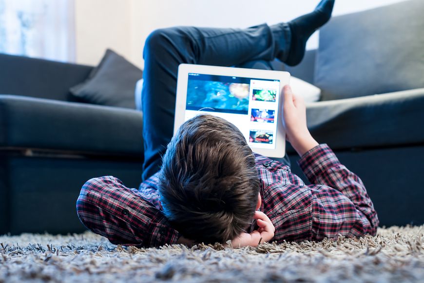 Das Bild zeigt einen Jungen, der etwas auf einem Tablet liest