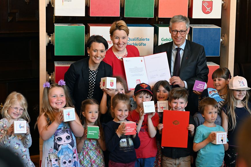 Ein Gruppenfoto mit Franziska Giffey, Kindern und vielen bunten Würfeln mit Sprüchen zum Gute-Kita-Gesetz