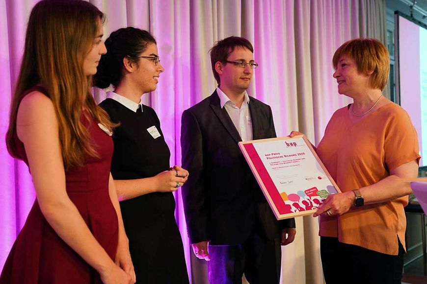 Das Bild zeigt Caren Marks bei der Übergabe eines Preises an Jugendliche