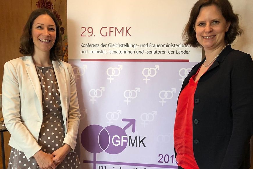 Juliane Seifert und Anne Spiegel vor einem Aufsteller mit der Aufschrift 29. GFMK