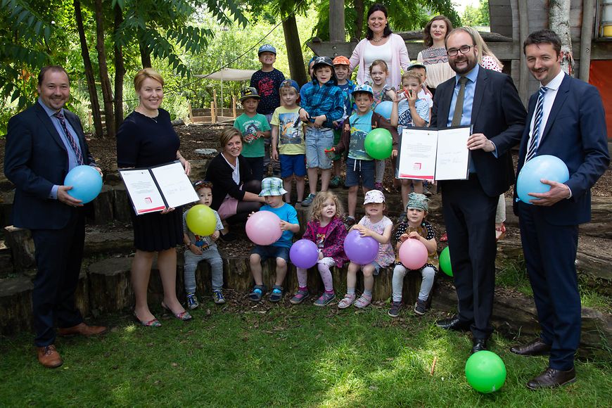 Franziska Giffey und Christian Piwarz zusammen mit Kindern als Gruppe mit den Gute-Kita-Verträgen im Grünen