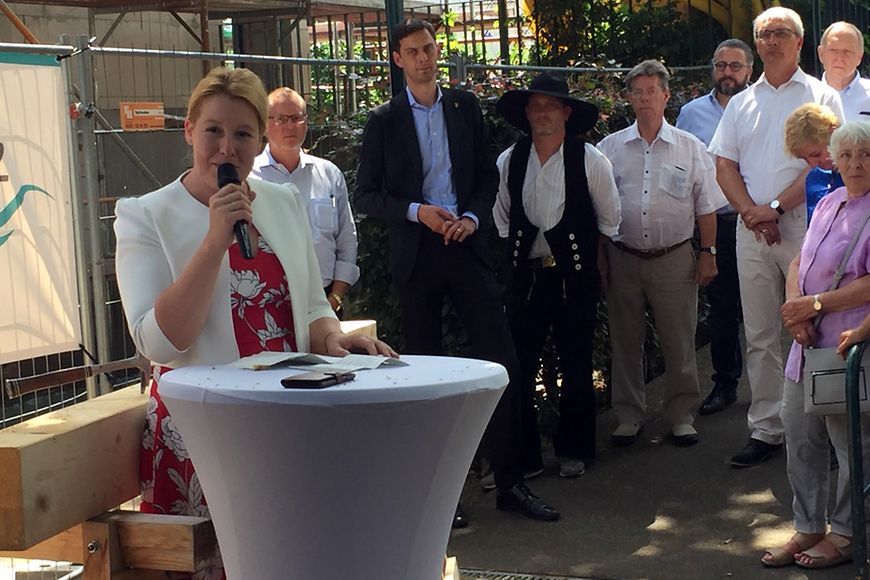 Franziska Giffey mit Mikrofon an einem Stehtisch bei dem Richtfest der Ricam Hospiz Stiftung 