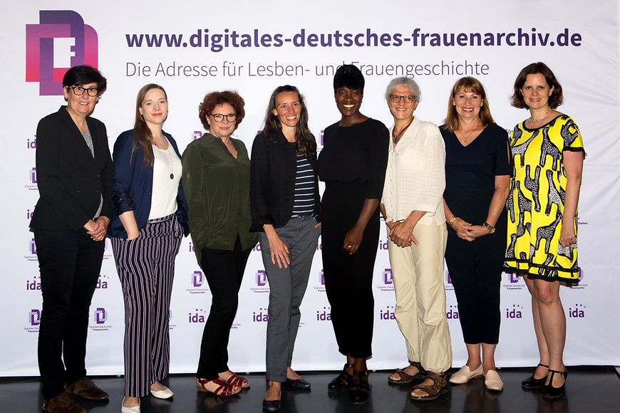 Eine Gruppe von Frauen vor einer Wand mit der Aufschrift: Digitales Deutsches Frauenarchiv