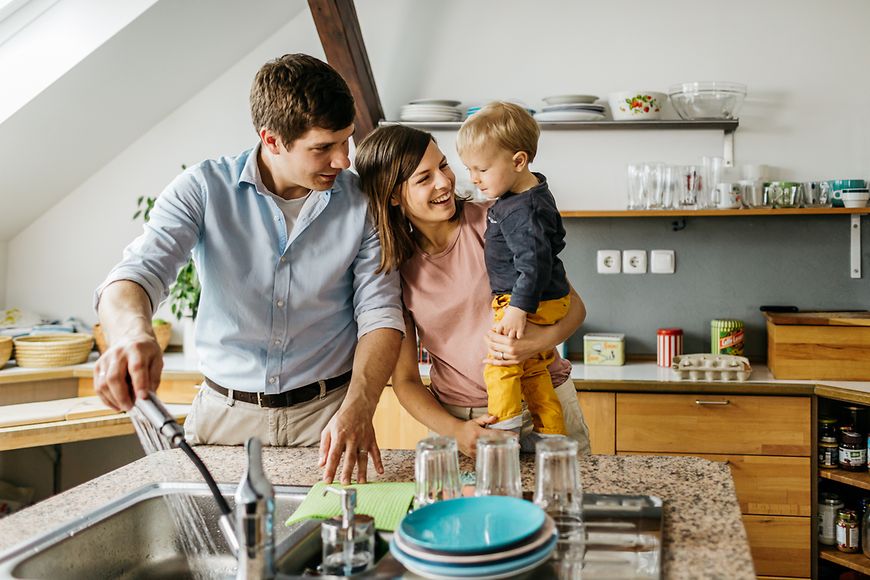 Eine junge Familie steht in der Küche beim Abwasch