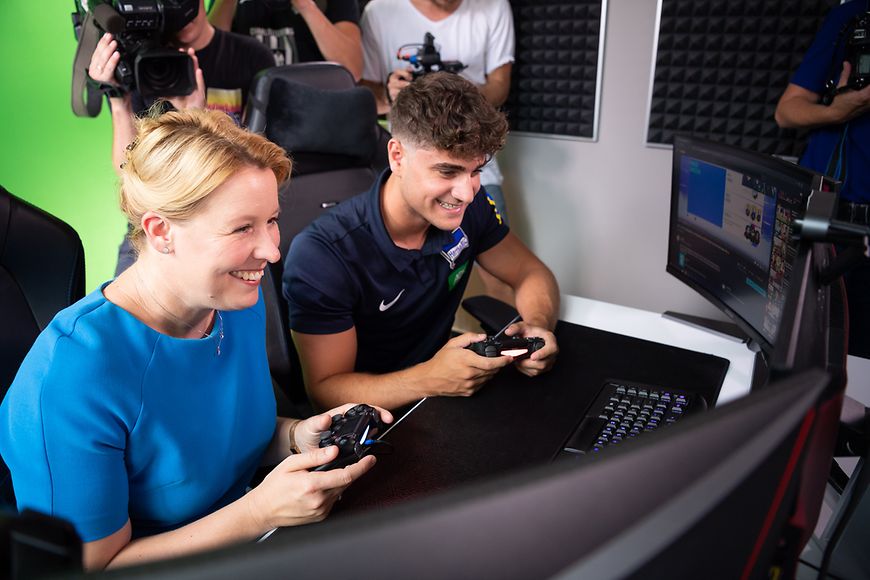 Dr. Franziska Giffey sitzt mit einem eSportler am Computer