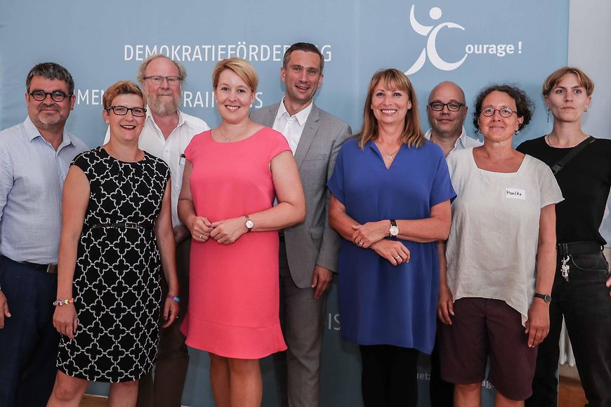 Eine Gruppe von Menschen vor einer Wand mit den Wörtern Demokratieförderung und Courage