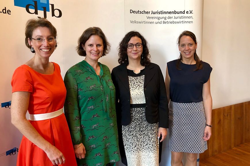 Vier Frauen vor einem Aufsteller mit der Aufschrift Deutscher Juristinnenbund