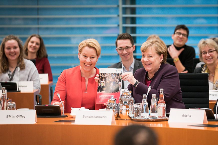 Das Foto zeigt Franziska Giffey und Angela Merkel, die gemeinsam die Broschüre zur Jugendstrategie hochhalten