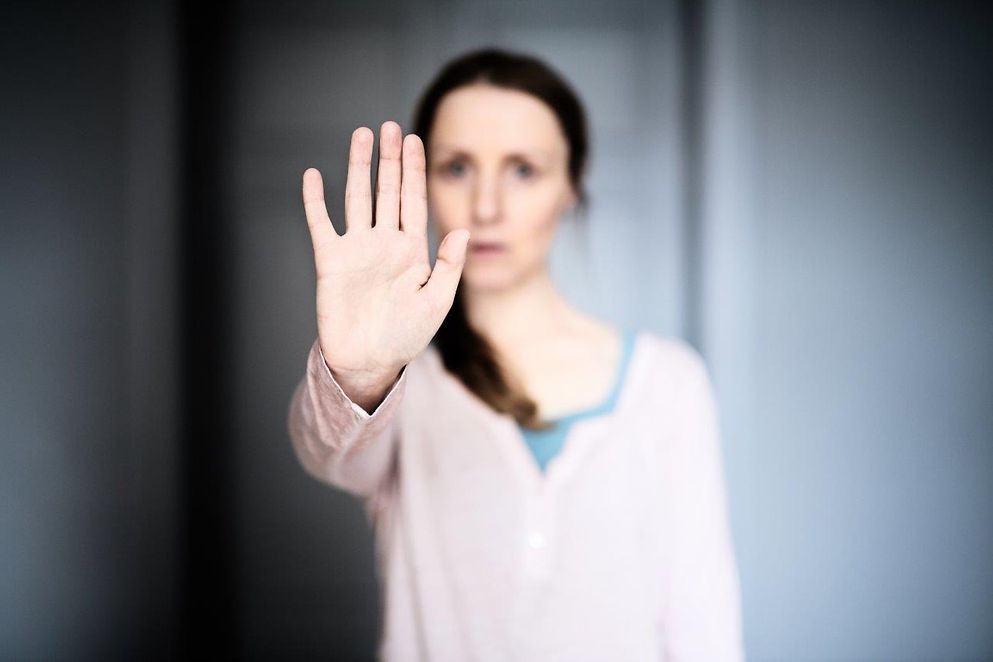 Eine Frau streckt ihren Arm aus um "Stopp" zu signalisieren.