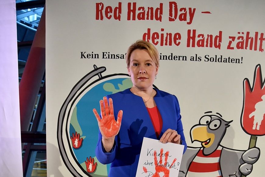 Dr. Franziska Giffey zeigt ihre rot gefärbte Hand. Sie trägt ein Schild mit der Aufschrift "Kindern ihre Kindheit".