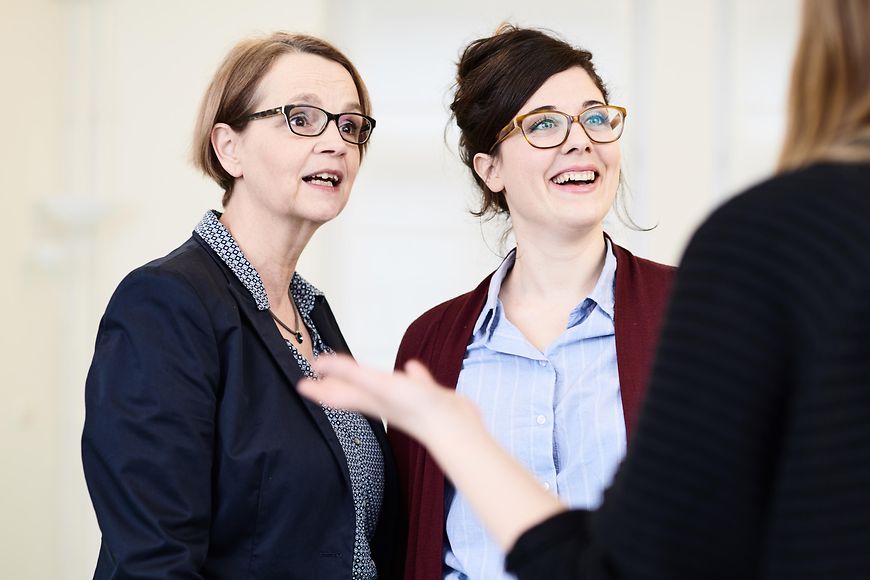 Drei Frauen in Businesskleidung diskutieren.