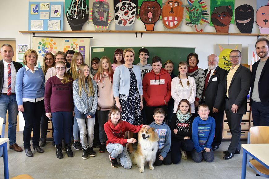 Gruppenfoto: Dr. Franziska Giffey mit Schülerinnen und Schülern und Erwachsenen in einem Klassenraum.