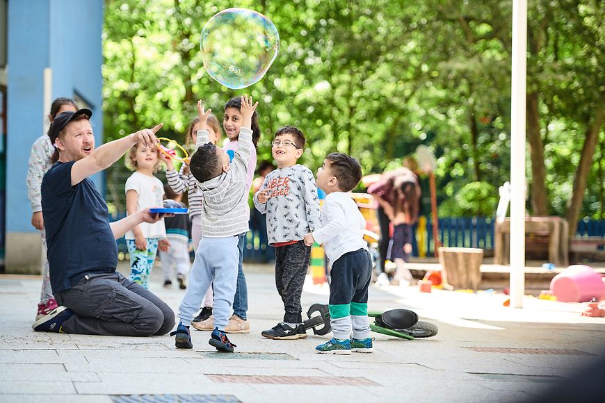 Ein Erzieher betreut eine Gruppe kleiner Kinder