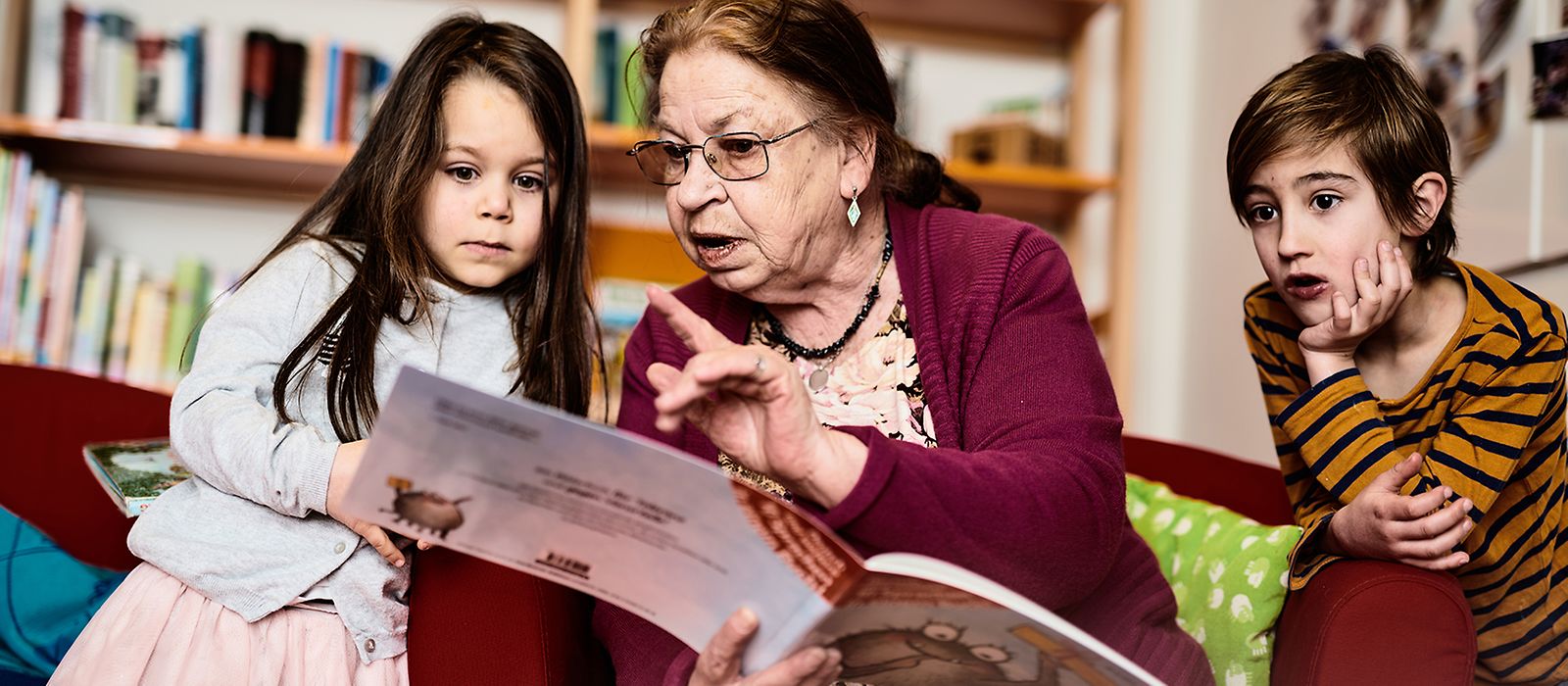 Eine ältere Frau liest zwei Kindern vor