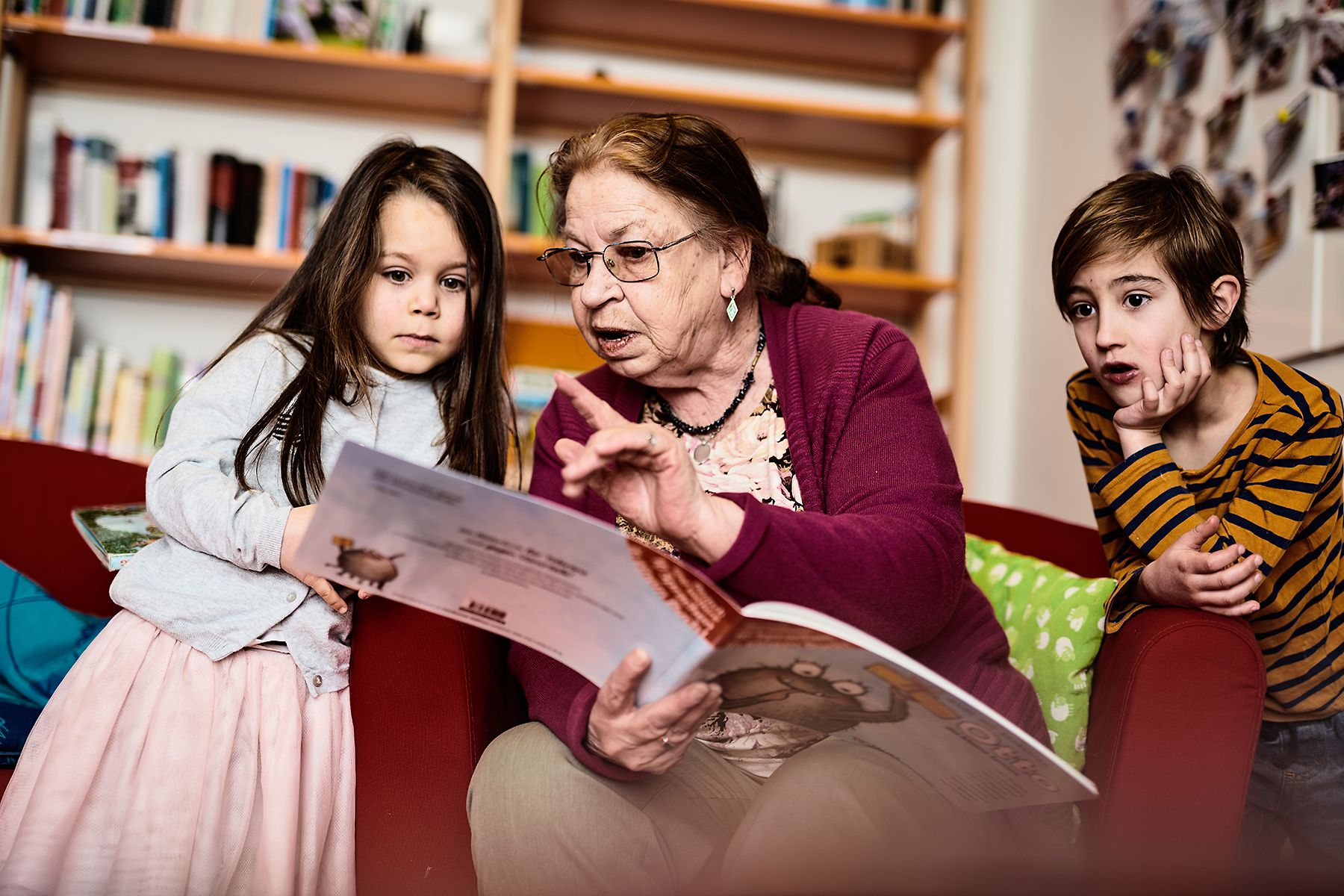 Eine ältere Frau liest zwei Kindern vor